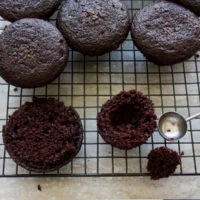 half a chocolate muffin being hollowed out to be filled with cream