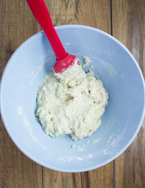 vanilla cake batter being folded with a silicon spatula