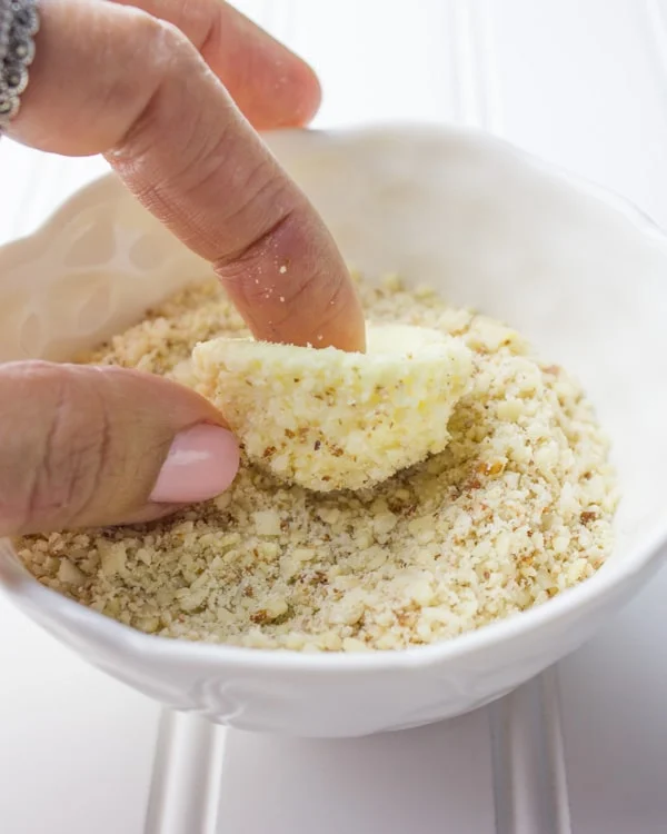 Greek Yogurt Cheesecake Bite being rolled in almond crunch topping