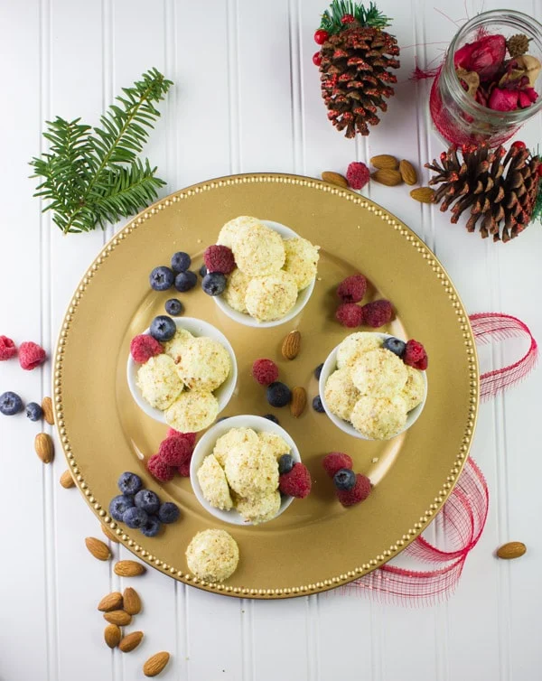 overhead shot of Almond Crunch Greek Yogurt Cheesecake Bites in white cups arranged on a golden plate