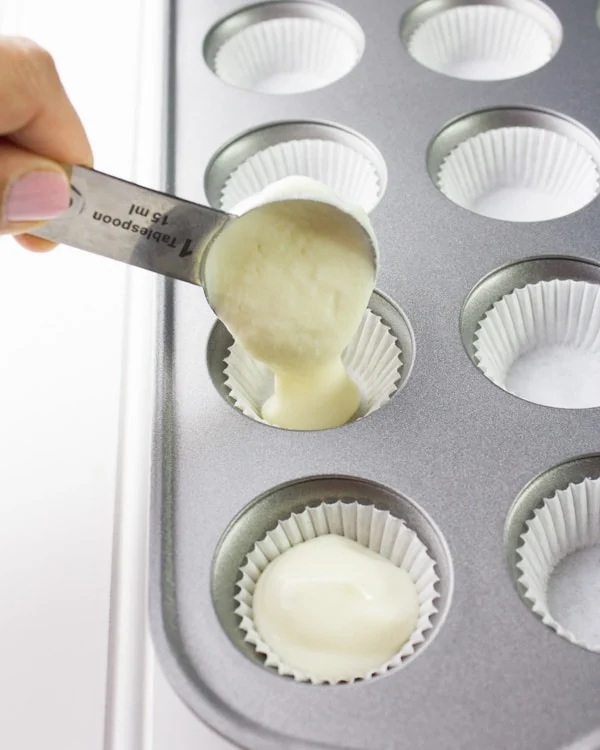 Greek yogurt filling being spooned into a lined muffin tin