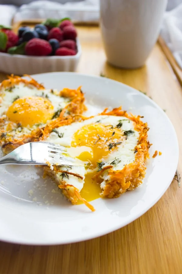 Close-up of Baked Eggs in Sweet Potato Crusts with some runny egg yolk oozing onto the plate.