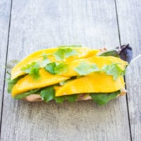 half a ciabatta bun topped with mango slices and cilantro