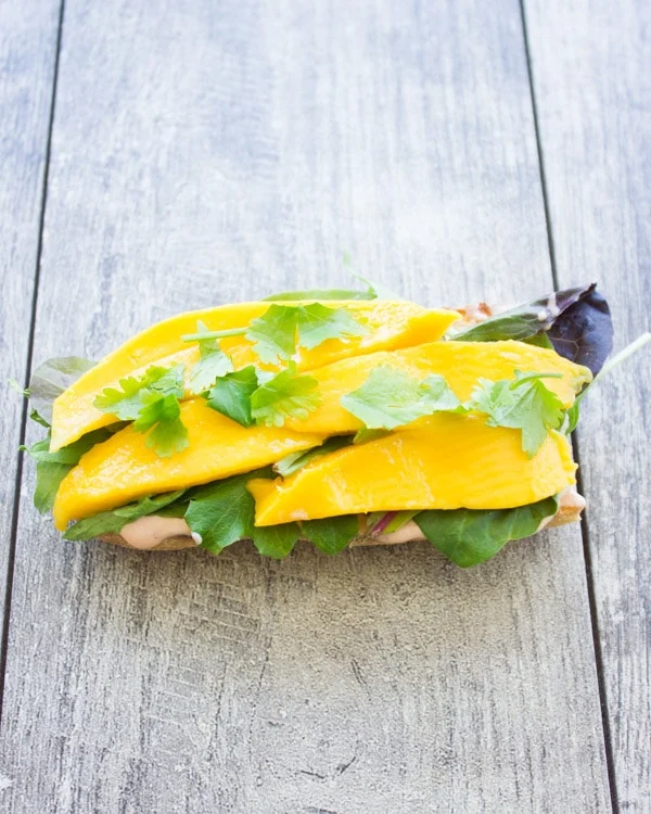 half a ciabatta bun topped with mango slices and cilantro