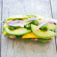 half a ciabatta bun topped with mango, avocado slices, red onion rings and fresh cilantro