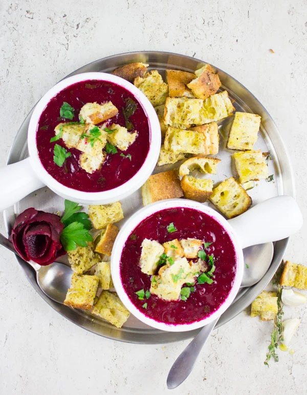 overhead shot of two bowls of Russian Beetroot Soup with croutons on the side