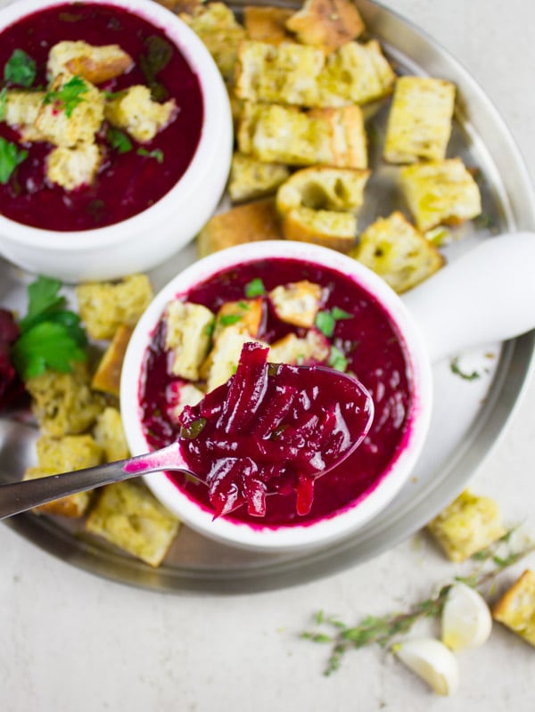a spoon being balanced over two bowls of Russian Beetroot Soup