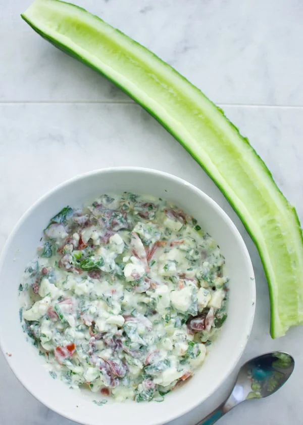 bowl of feta cream and a deseeded cucumber cut lengthwise ready to be filled with feta cream