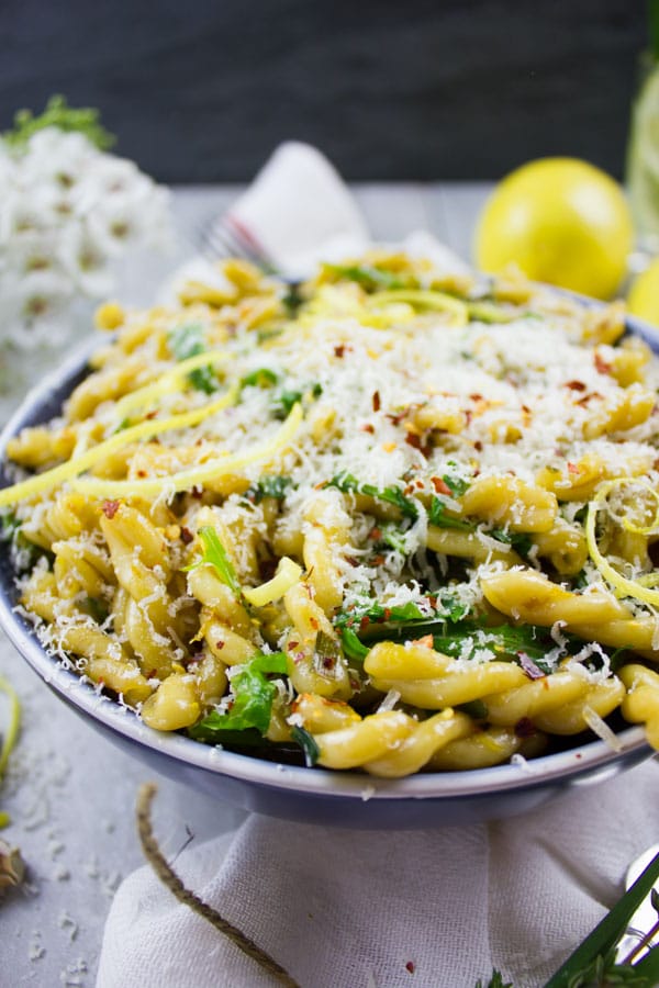 side view of a plate of garlic lemon pasta sprinkled with parmesan cheese and lemon zest