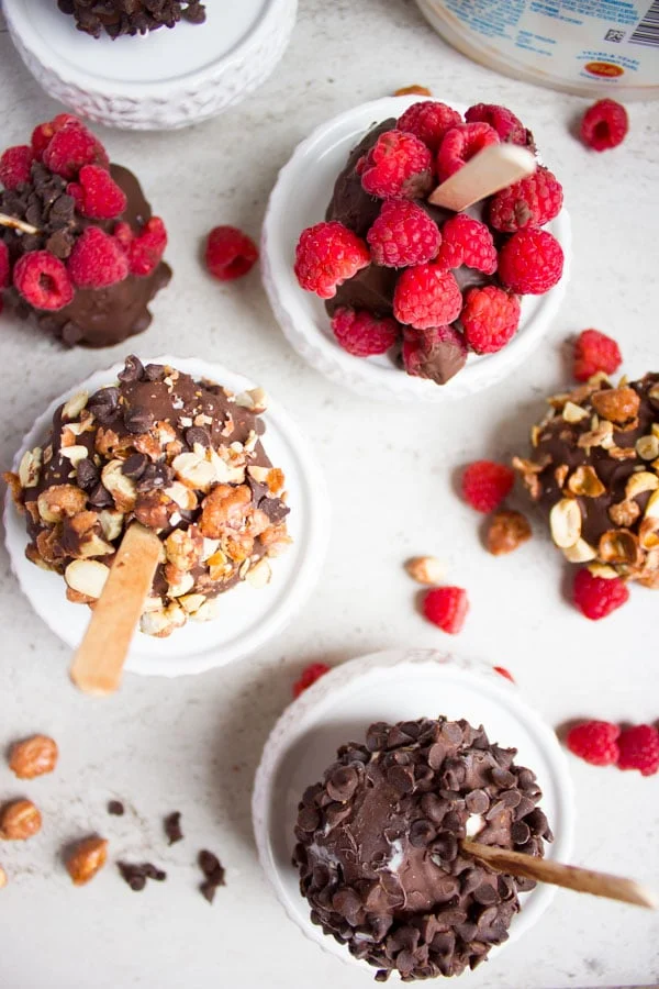 top view of raspberry topped ice cream pops and some nuts.