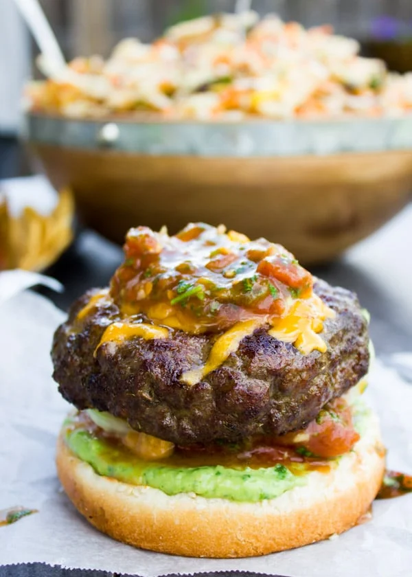 Open lamb burger with melted cheddar cheese and salsa spread on top of the juicy lamb burger patty.