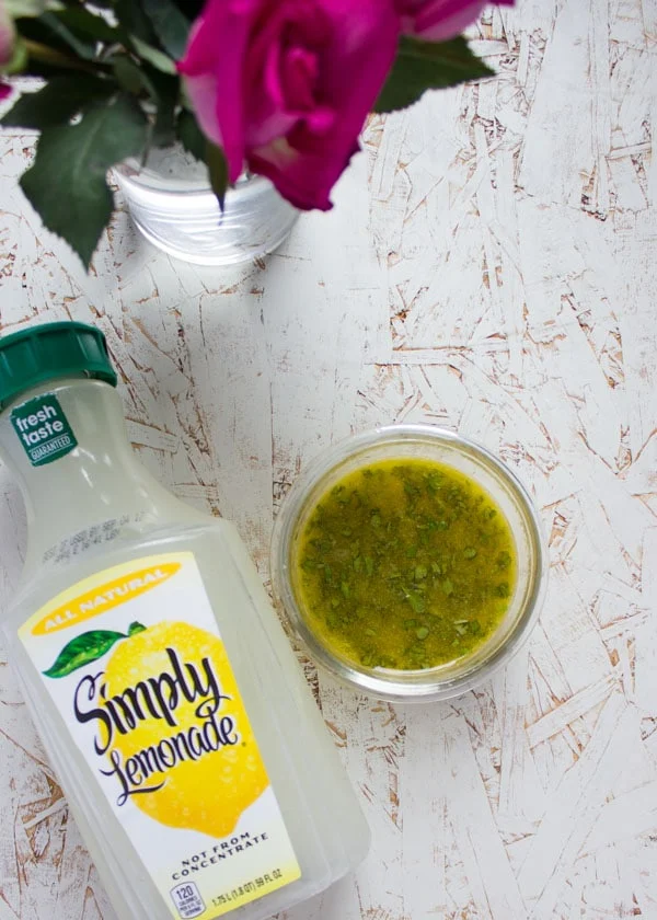 Sweet Zesty Lemonade Dressing in a small glass bowl next to a bottle of lemonade.