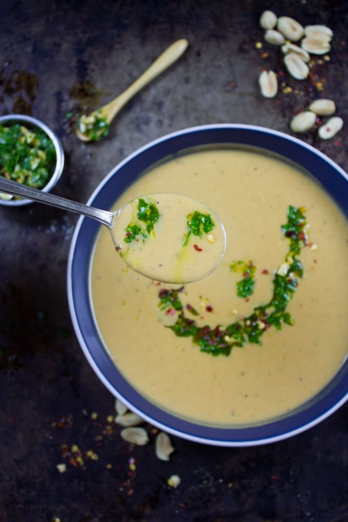 a spoon full of Peanut Soup over a bowl of soup
