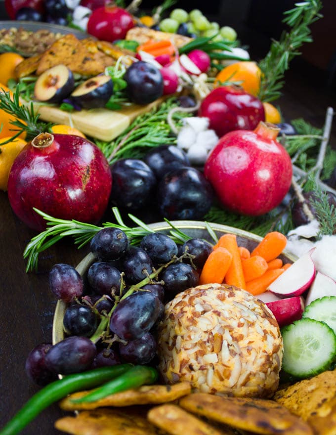 a nut-covered cheddar cheese ball nestled in a bowl of fruit