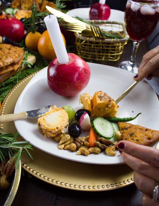 a plate with cheese, homemade pita chips, sliced veggies and candied pecans and cashews