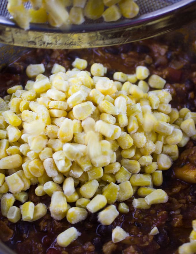 corn being added to a pot of veggie chili