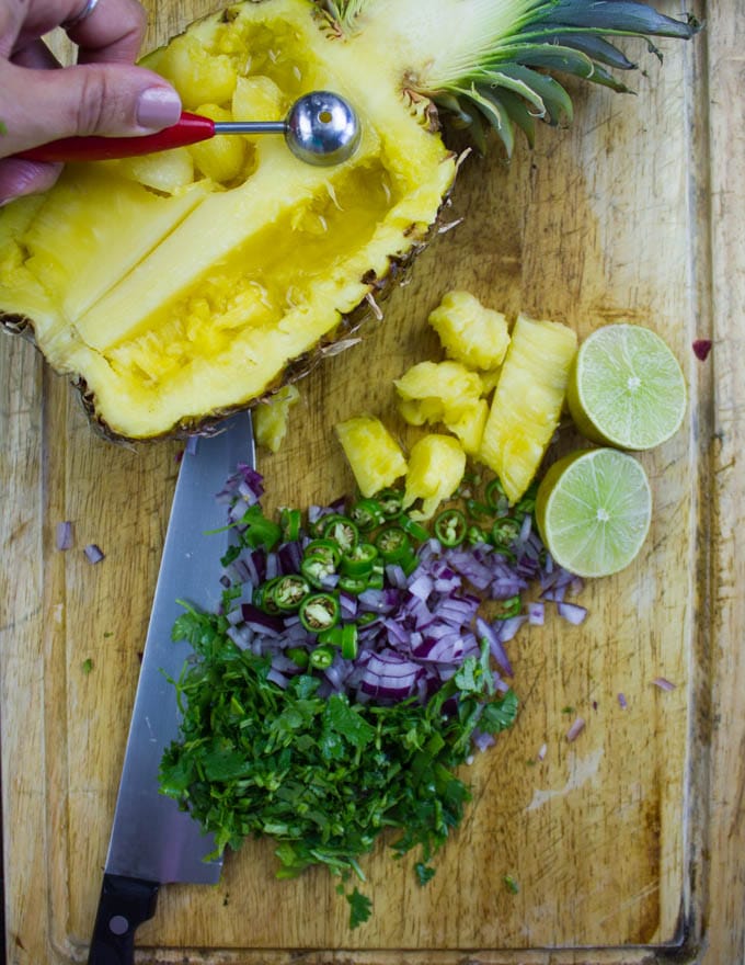 half a pineapple being hollowed out to fill with salsa