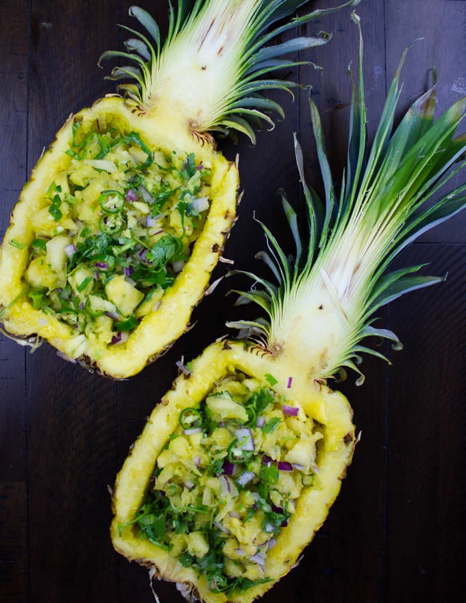 two halved pineapples stuffed with fresh pineapple salsa