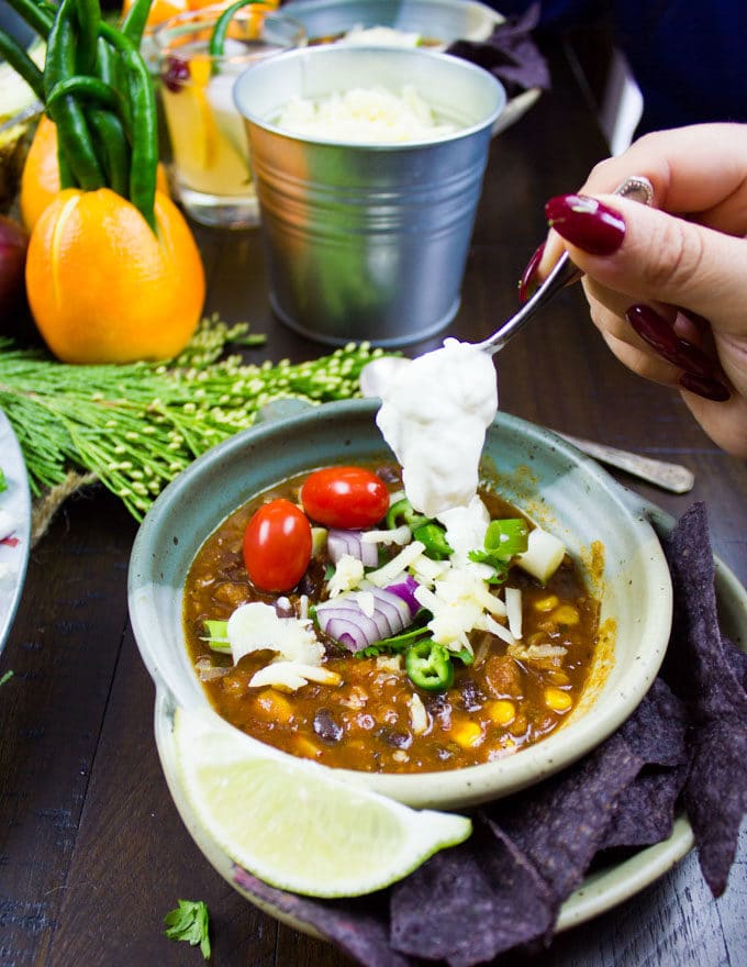 sour cream being spooned on top of a bowl of vegetarian chili