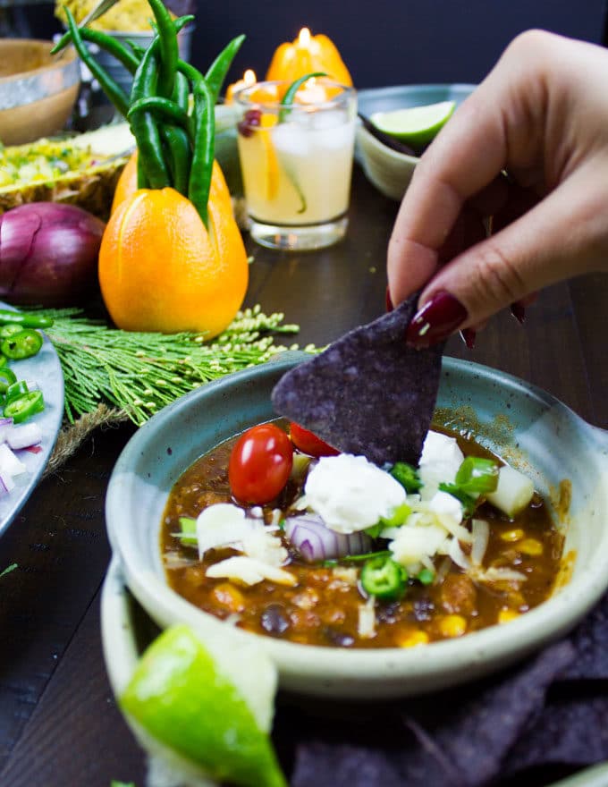 a nacho chip being dipped into a bowl of vegetarian chili