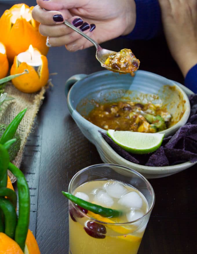 a fall cocktail and a half-eaten bowl of veggie curry on black table