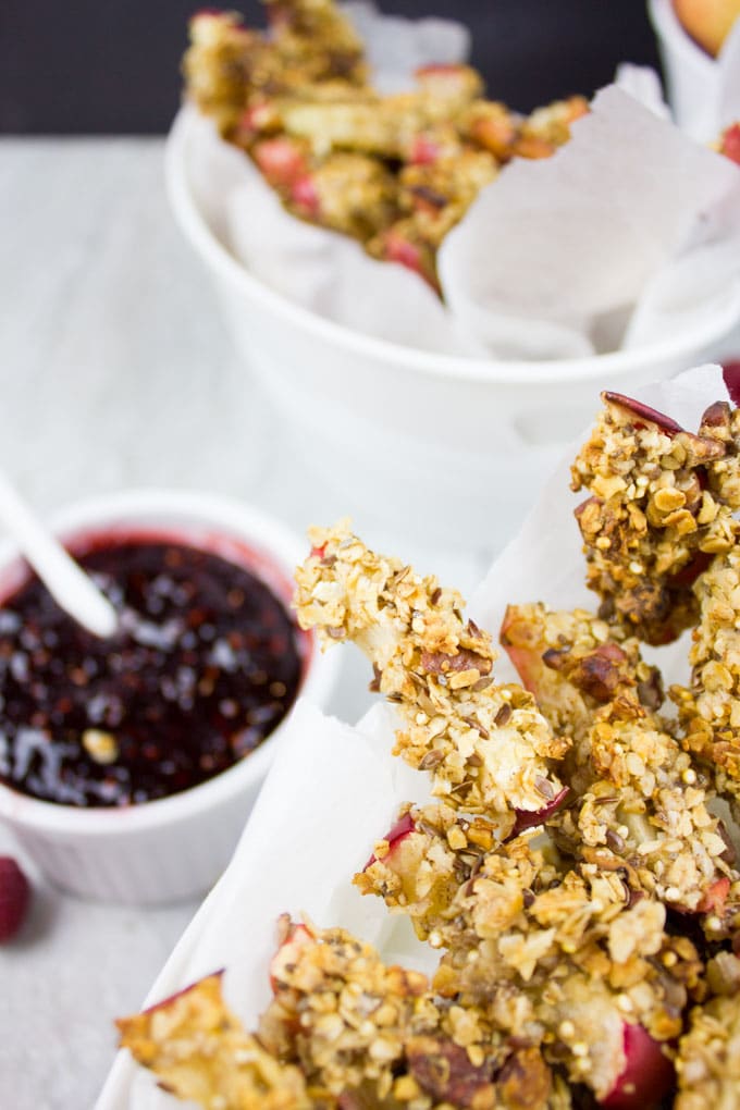 baked apple fries arranged in a paper-lined box with a side dish of raspberry sauce next to it