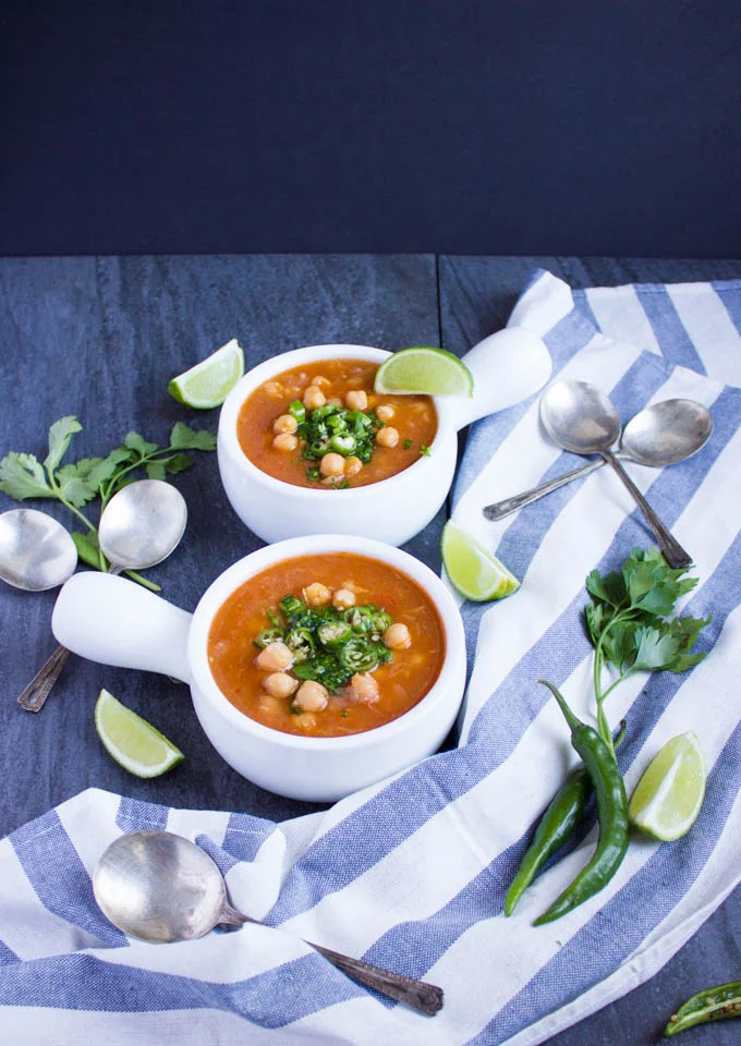 two small white bowls with Soothing Garlic Chickpea Soup next to a striped napkin