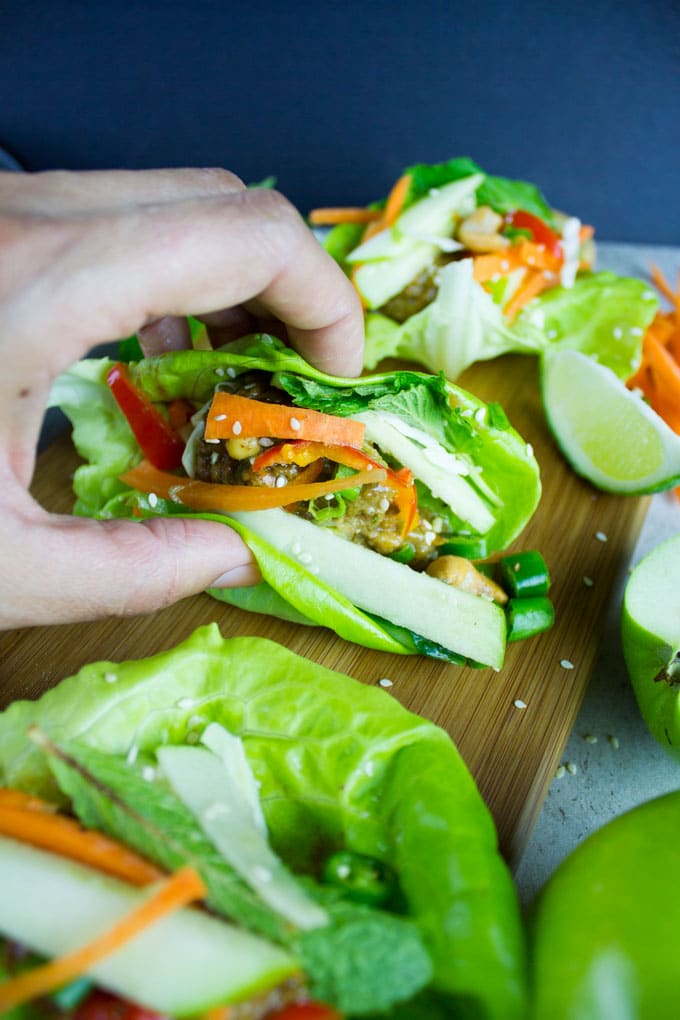 a hand reaching for Thai Chicken Meatballs with Apple Peanut Sauce on a wooden board