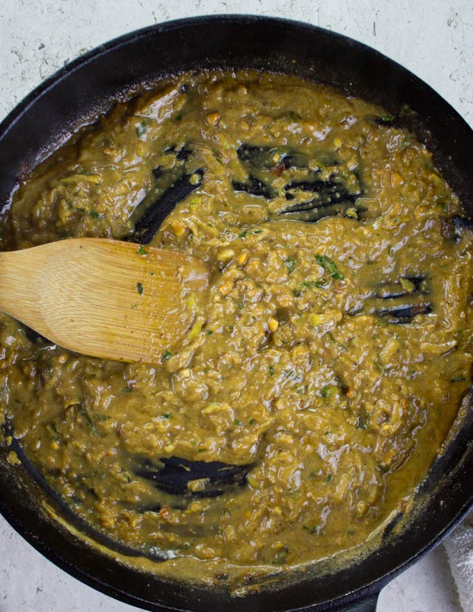 Apple peanut sauce being stirred in a black skillet