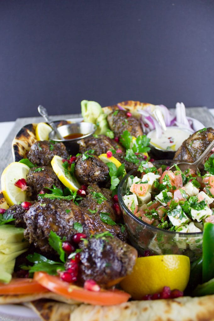 side view of chicken shawarma platter served on naan bread together with two small dishes with different Middle Eastern Sauces