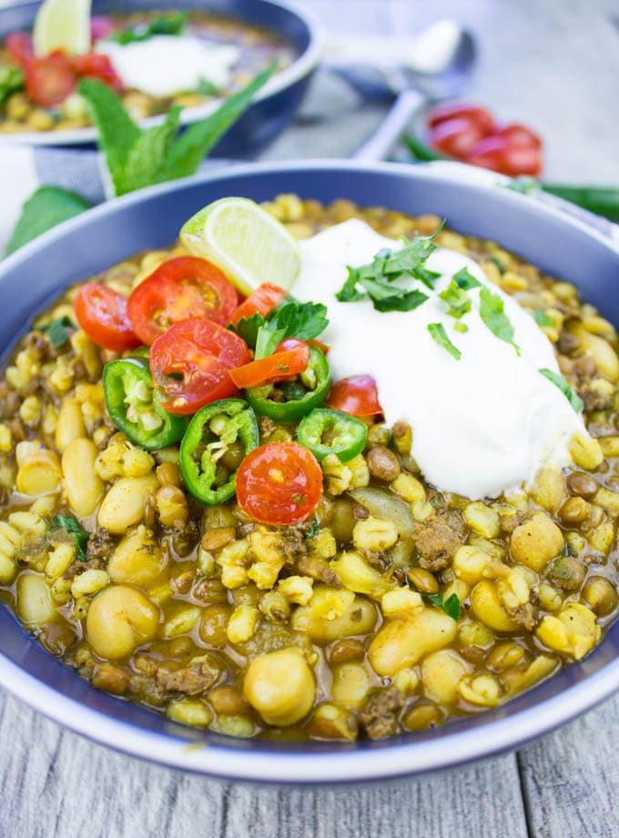 close-up of a bowl of Moroccan Lentil Soup with lamb and turmeric topped with tomatoes and sour cream