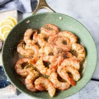 The shrimp is added in a single layer to a skillet at high heat for cooking