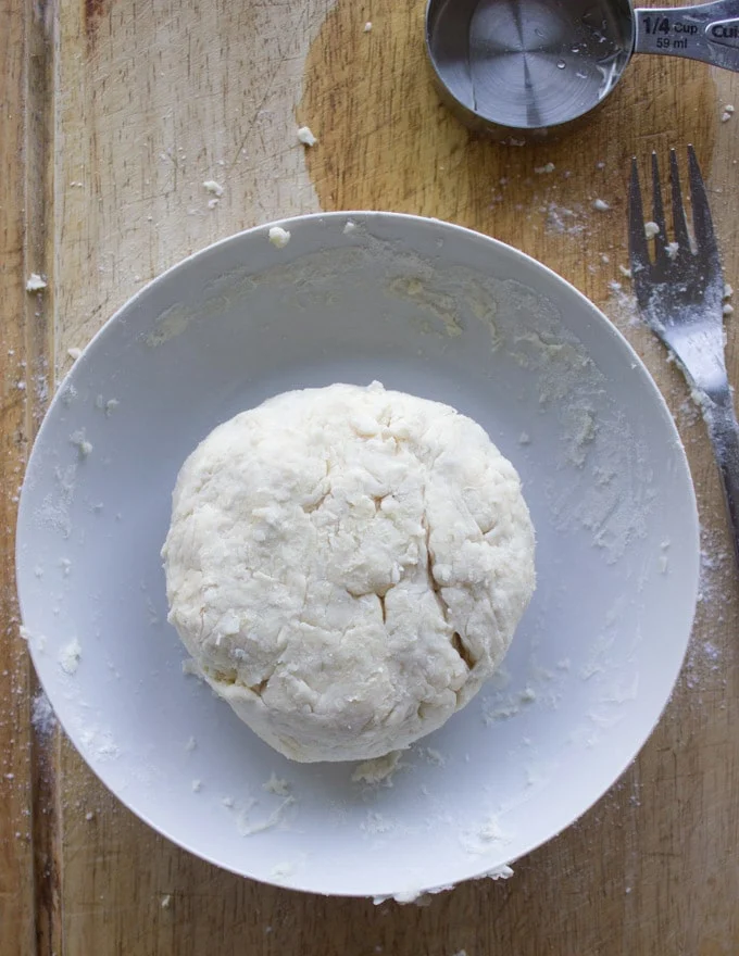homemade pie dough shaped into a disk in a bowl