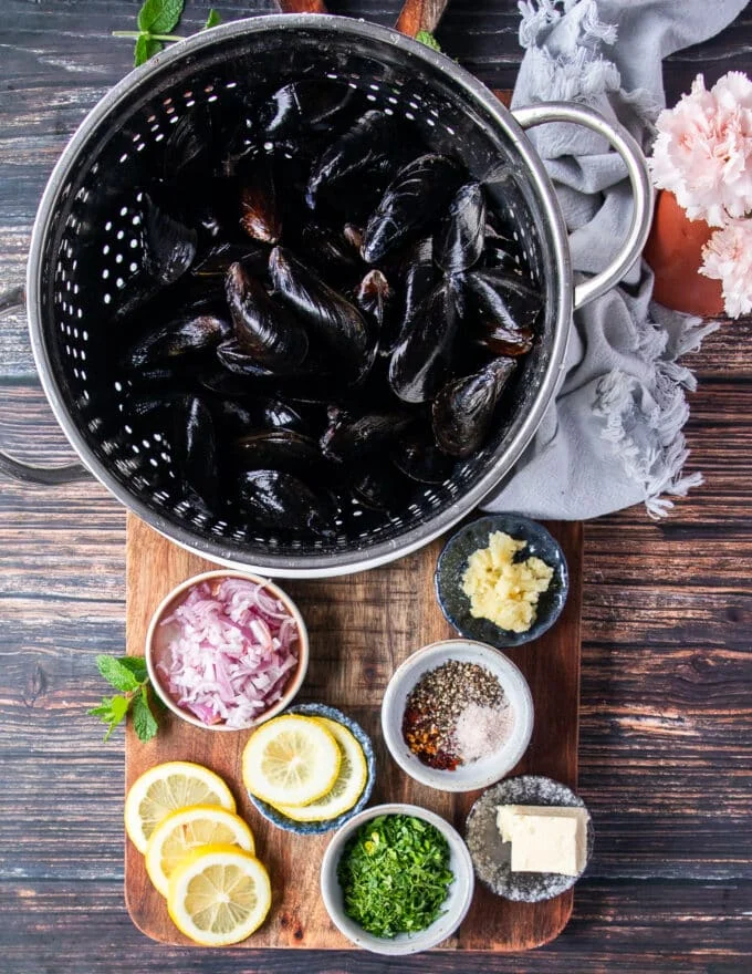 ingredients needed to make a mussels recipe on a wooden board