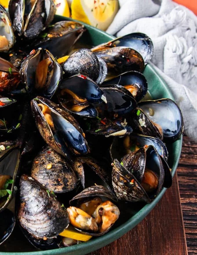 half a plate of mussels cooked in garlic and lemon with a saucy broth