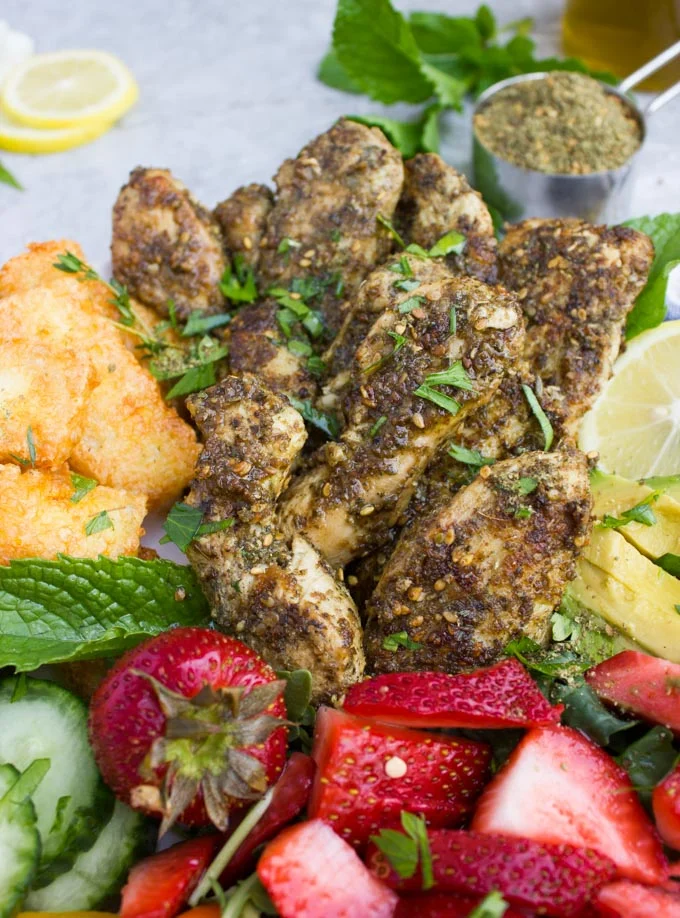 close-up of a bowl of Zaatar Chicken Salad with Fried Halloumi Cheese, cucumbers and strawberries