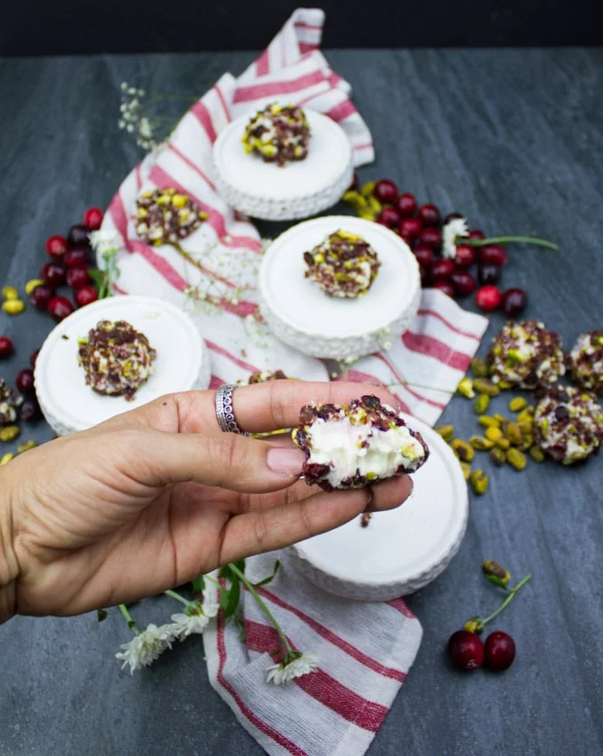 A hand showing a bitten piece of mini cheesecake bite.