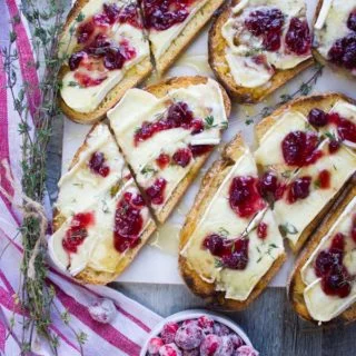 Top view and close up of two baked brie toats with cranberries and drenched in a honey drizzle