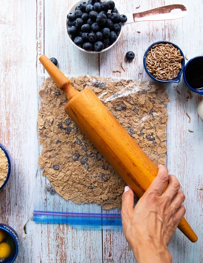 A rolling pin over a ziploc bag crushing the bran cereal
