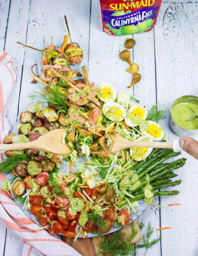 two hands holding a serving spoon and serving salmon salad