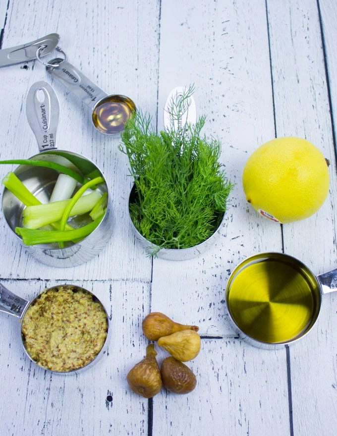Sweet Dill Dressing ingredients showing olive oil in a cup, some figs, a lemon, some dill in a cup, scallions in a cup and a spoon of honey