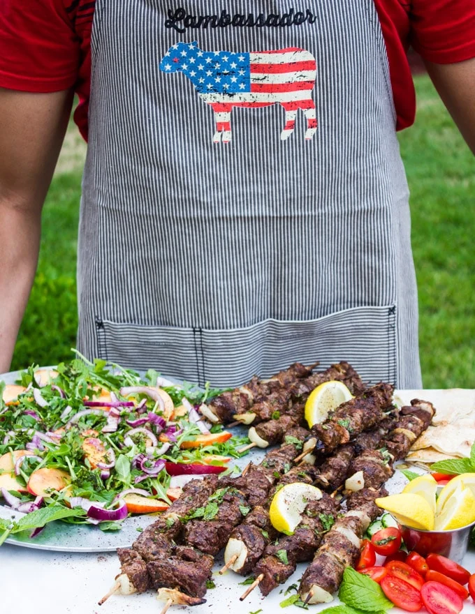 The grill master wearing a lamb apron and holding the grilled lamb platter to start the BBQ party