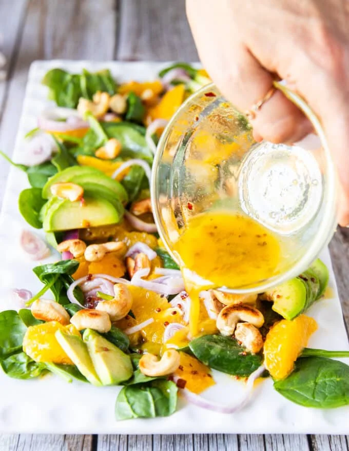 orange dressing is poured over the orange salad