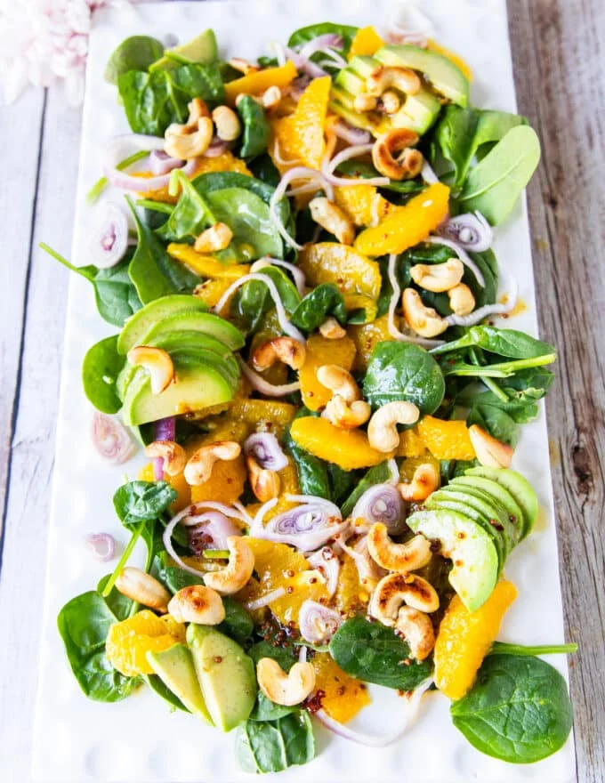 A plate of orange salad with avocado, nuts, orange segments