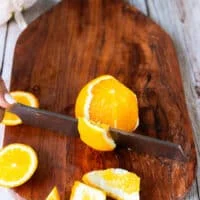 Segmenting the orange, the knife going down the orange to slice the white and skin off