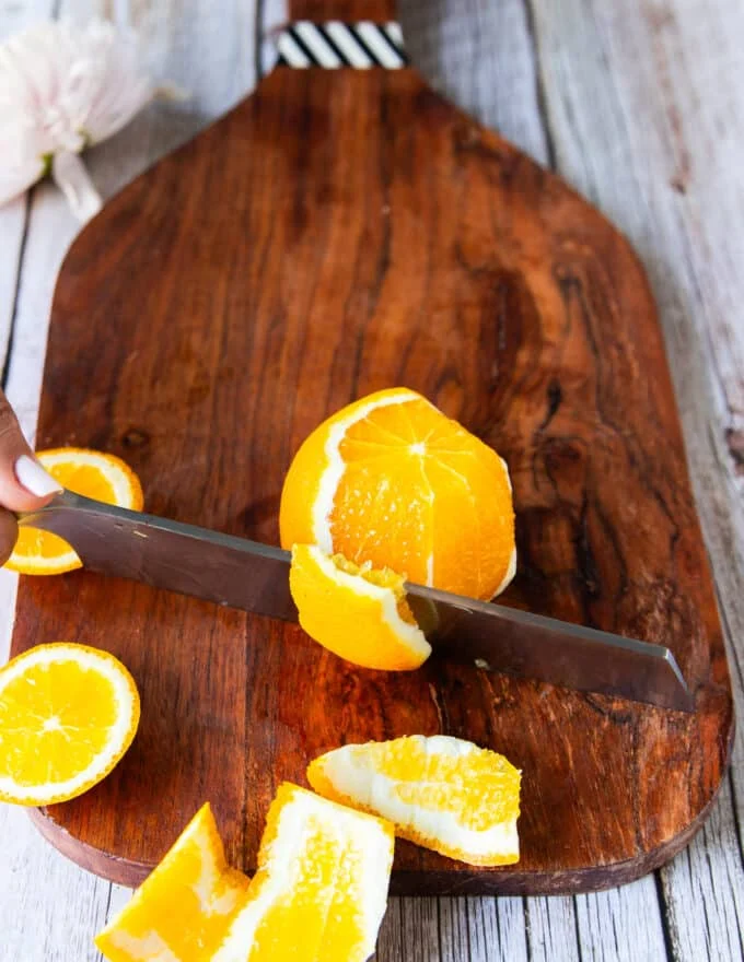 Segmenting the orange, the knife going down the orange to slice the white and skin off