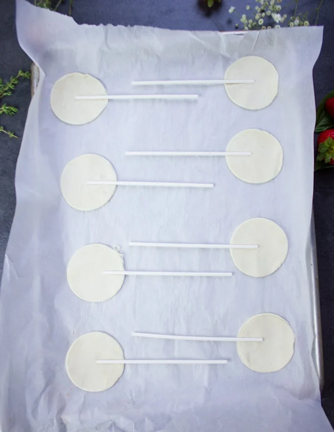 A tray of bottom crusts for hand pies with lollipop sticks