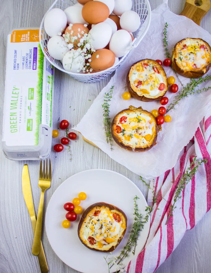 A plate with one baked egg in bread bowl and a carton of eggs next to it