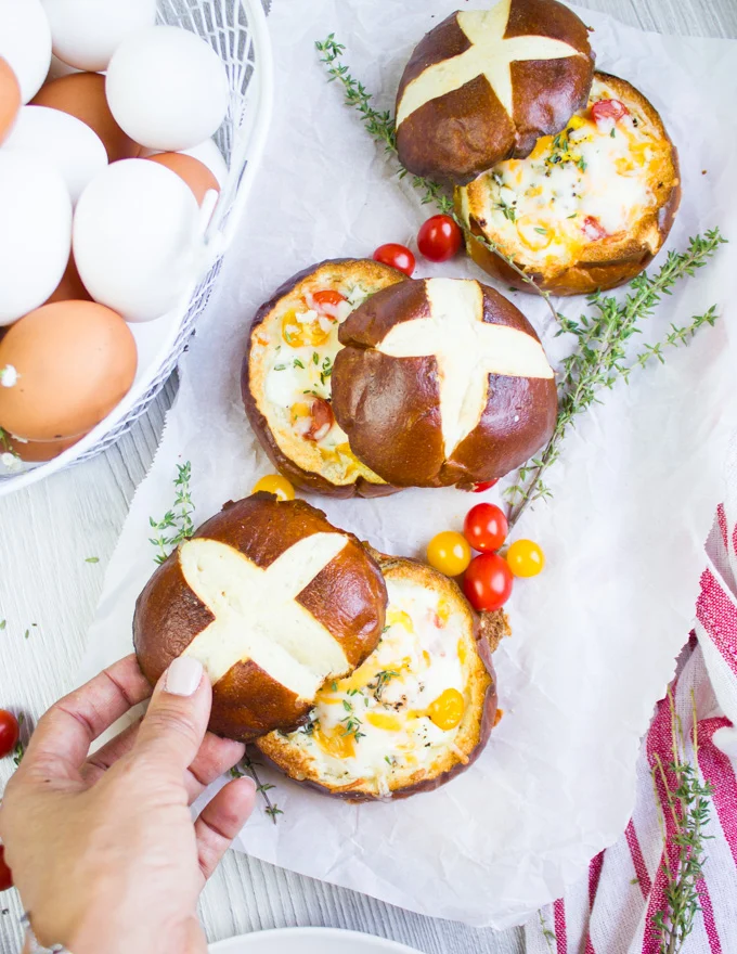 A hand placing the bread tops over the baked eggs