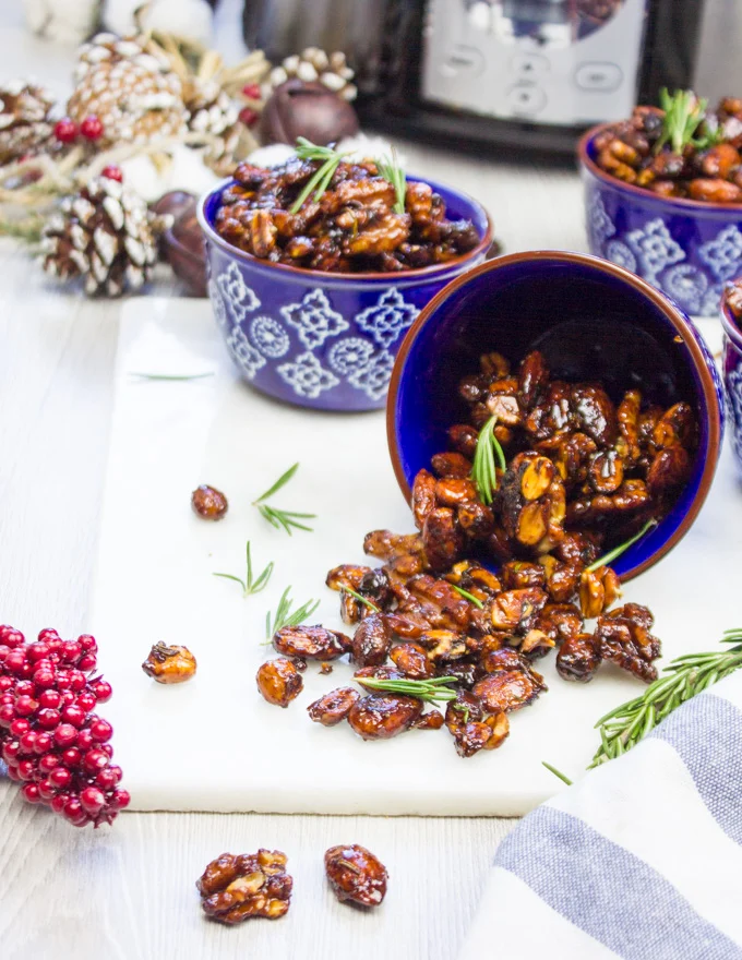 Mixed nuts or spiced nuts poured out of a bowl on to a white marble
